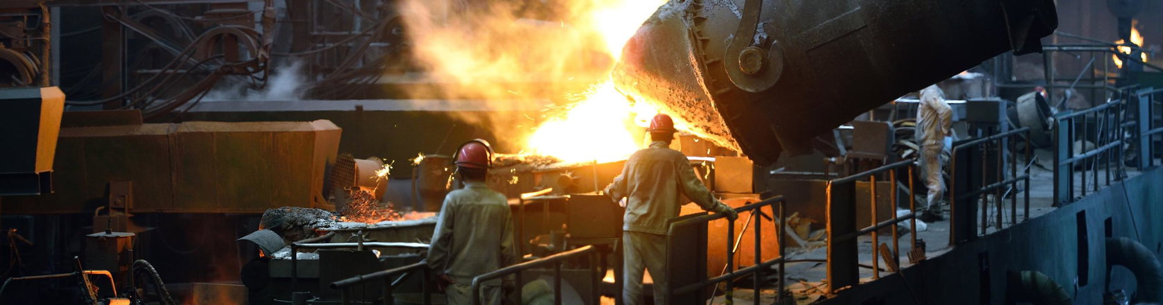 Pouring liquid molten metal to casting mold in front of two workers